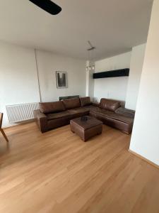 a living room with a brown leather couch and wooden floors at Pilsen flat in Pilsen