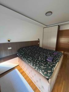 a bedroom with a large bed with a green blanket at Apartman Akademska Četvrt in Čačak +10 photos