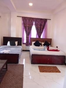 a bedroom with two beds and a window with purple curtains at The nest haputale in Haputalegama