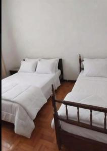 two beds in a room with white sheets and pillows at Recanto Esperança - Na Feirinha do Alto in Teresópolis