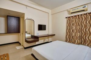 a bedroom with a bed and a sink and a mirror at Hotel Rajpurush in Kolhapur