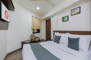 a hotel room with a bed and a chair at Hotel JK Regency, Mumbai International in Mumbai