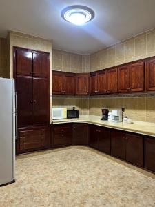 a kitchen with wooden cabinets and a white refrigerator at Maison in Berkane