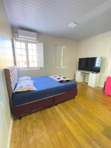 a bedroom with a bed in a room with a flat screen tv at Casa central in Rosário do Sul +3 photos