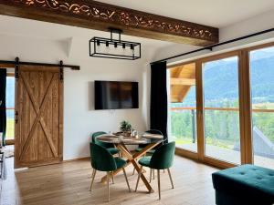 a dining room with a table and green chairs at Apartamenty Butorowy in Kościelisko