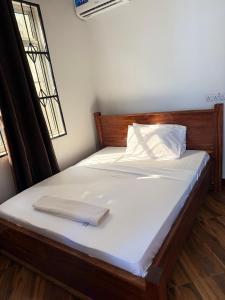 a bed with white sheets and a book on it at Mangi Mangi Accomodation in Nungwi