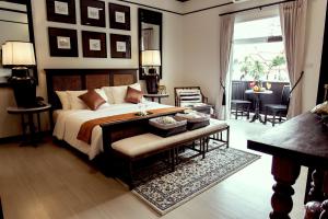 チェンマイにある99ザ ヘリテージホテル-SHA Extra Plus Certifiedのベッドルーム1室(ベッド1台、ベンチ、テーブル付)
