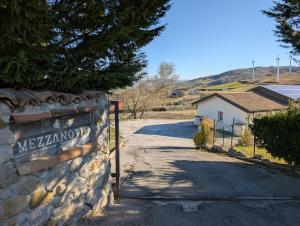 a sign on a stone wall with a road at Bed and Breakfast Mezzanotte in Balvano