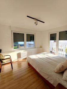 ein weißes Schlafzimmer mit Bett und Fenstern in der Unterkunft Sanhe in Rollingen