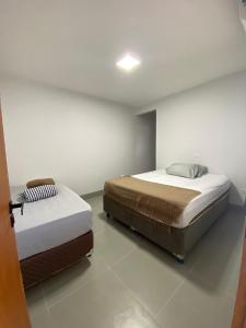 two beds sitting in a room with at Casa com piscina praia do ervino in São Francisco do Sul +3 photos