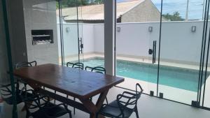 a dining room with a table and chairs and a swimming pool at Casa com piscina praia do ervino in São Francisco do Sul