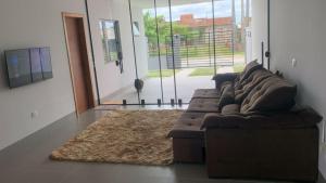 a living room with a brown couch and a rug at Casa com piscina praia do ervino in São Francisco do Sul