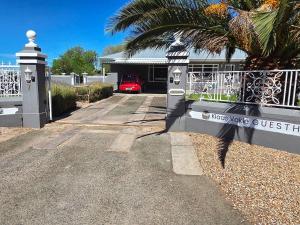 a gate to a house with a red car in the driveway at Klaas Vakie Guesthouse in Beaufort West
