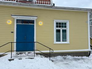 a yellow house with a blue door in the snow at Sentralt og koselig in Kristiansand