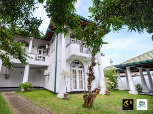 a white house with a tree in the yard at Azure Heaven Villa in Wennappuwa