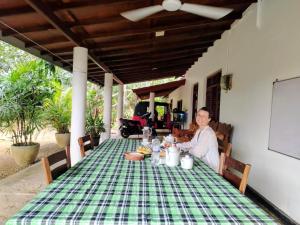 a woman sitting at a table with a green table cloth at White Villa - Homestay in Tangalle +57 photos