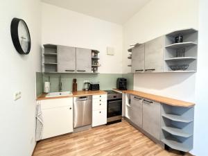 a kitchen with white cabinets and a clock on the wall at Ferienwohnung am Altmarkt, für bis zu 4 Personen, 55qm in Cottbus