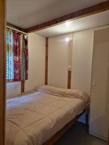 a small bedroom with a bed and two windows at Bungalows Prados Abiertos in Mombeltrán