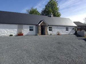 a white building with a driveway in front of it at Clontrain Cottage in Carrickmacross