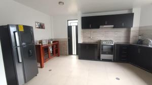 a kitchen with black cabinets and a refrigerator at Refugio Volcán Tungurahua in Ambato