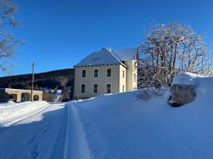 a snow covered road in front of a building at Alte Försterei Wildenthal - Ferienwohnungen in Eibenstock in Eibenstock