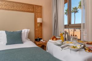 a hotel room with a bed with a tray of food on it at Kenzi Azghor in Ouarzazate
