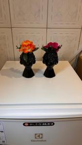 two vases with flowers on top of a appliance at Casa do João in Maricá