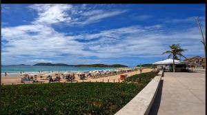 a beach with people sitting on the sand and the ocean at Jesaluguel-de-casa in Cabo Frio