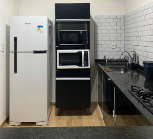 a kitchen with a refrigerator and a microwave at Jesaluguel-de-casa in Cabo Frio