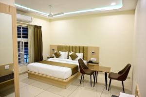 a bedroom with a bed and a table and chairs at SR Grand in Tumkūr