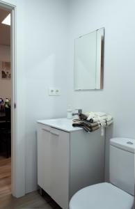 a white bathroom with a toilet and a sink at Suites TDJ Centro in Torredonjimeno