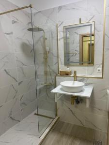 a bathroom with a sink and a shower with a mirror at Alex MNL lux Apartment 2 free parking in Bucharest