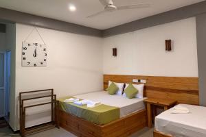 a bedroom with two beds and a clock on the wall at Jkl MahaOya Villa in Wayikkal +47 photos