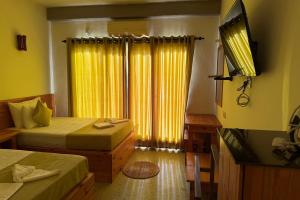 a bedroom with two beds and a window with yellow curtains at Jkl MahaOya Villa in Wayikkal