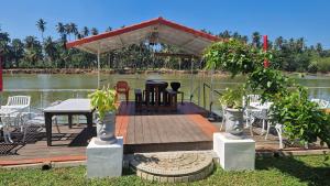 a wooden deck with a table and a pavilion on the water at Jkl MahaOya Villa in Wayikkal