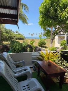 a patio with white chairs and a wooden table at Secret Lanta Guesthouse in Ko Lanta