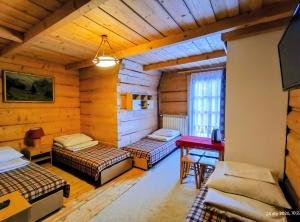 a room with two beds and a desk in it at CHAŁUPA Pokoje Gościnne in Poronin