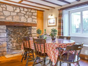 a dining room with a table with chairs and a stone wall at Pebbles in Castletown