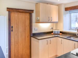 a kitchen with wooden cabinets and a sink at Pebbles in Castletown