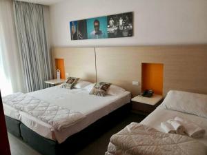 a hotel room with two beds and a tv at Hotel Kaos in Villaggio Pirandello