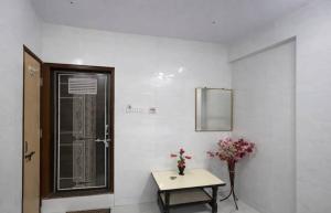 a room with a table and a door with a vase of flowers at Patel's Guest House in Surat