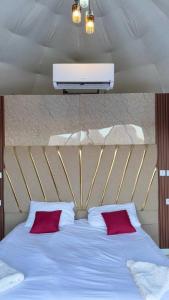 a bed with two red pillows and a light above it at Silent Sands in Wadi Rum
