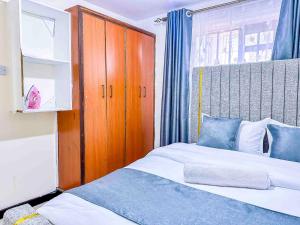 a bedroom with two beds and a wooden cabinet at GILGAL Homes in Kisii