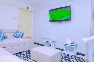 a living room with a couch and a tv on the wall at GILGAL Homes in Kisii