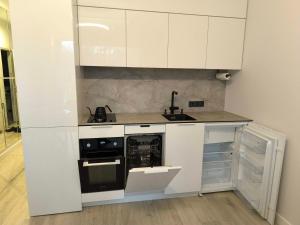 a white kitchen with a sink and a stove at Fly & Pool Apartment in Palanga