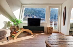 a living room with a television and two large windows at Himmelsnest in Bad Wildbad