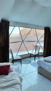 a room with two beds and a large window at Silent Sands in Wadi Rum +25 photos