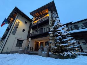a snow covered christmas tree in front of a building at Hotel Chalet Seggiovia in Pontechianale