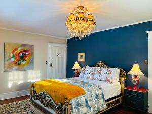 a bedroom with a bed with blue walls and a chandelier at The Farmhouse Manor B&B in St. Catharines