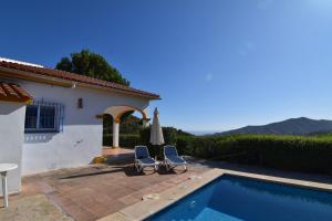 a house with a swimming pool and two chairs and an umbrella at Villa La Frasca with private Pool in Corumbela